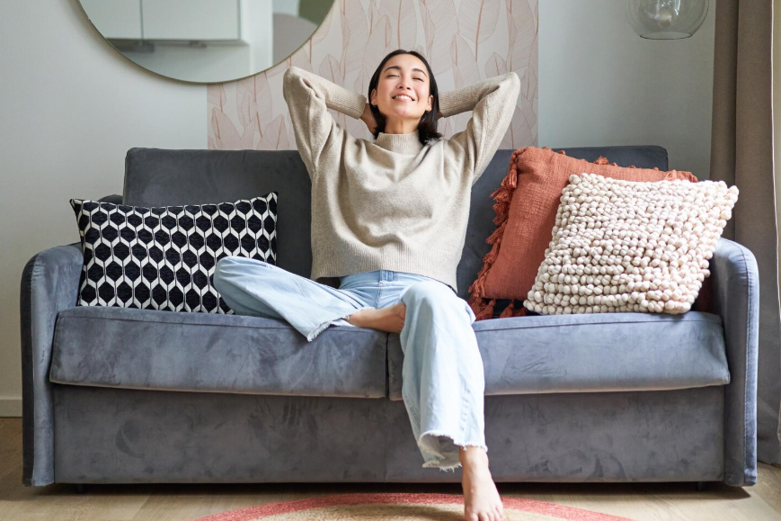 Woman relaxing on a couch at home, enjoying a sense of belonging.