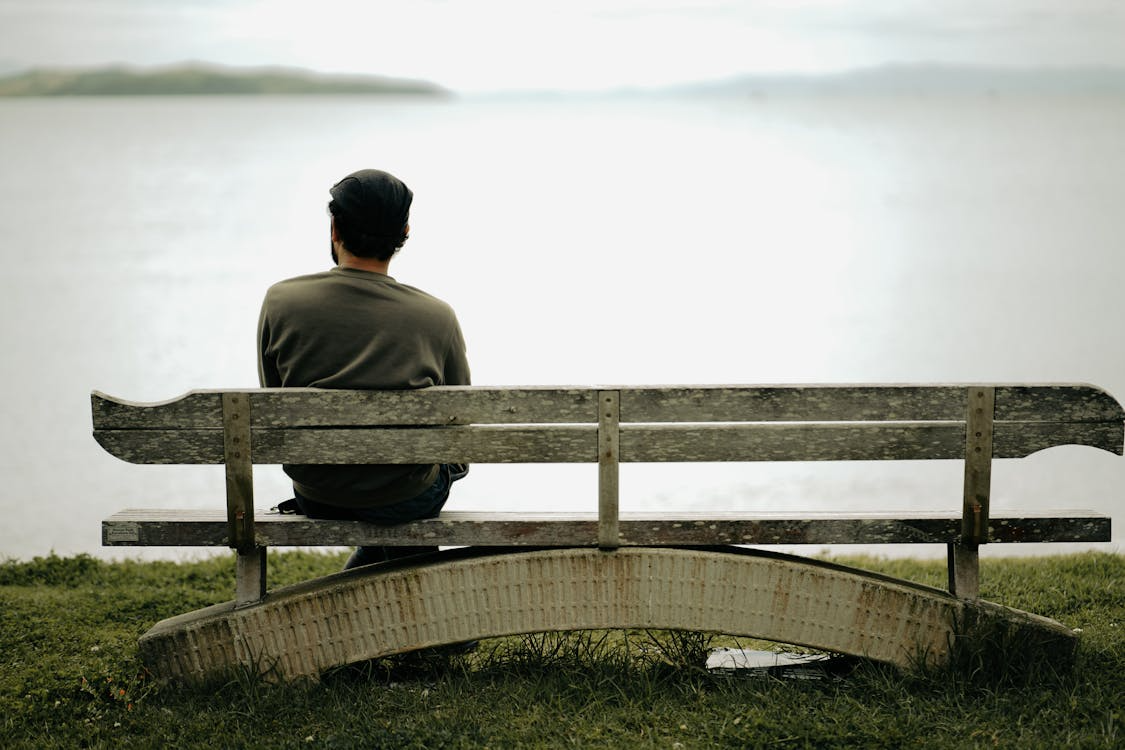 Person sitting alone on a bench reflecting on meaning, purpose, and life direction.
