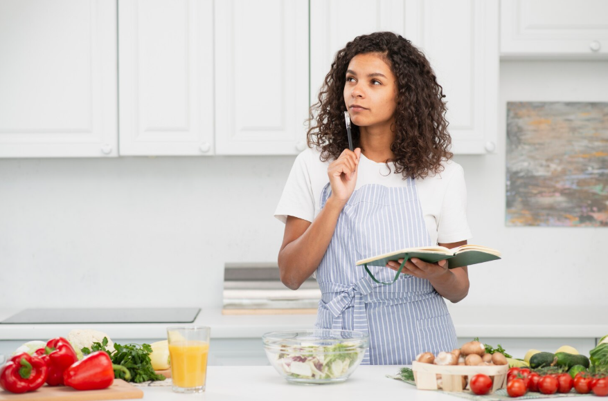 Person planning meals in kitchen, reflecting diet searches driven by control.